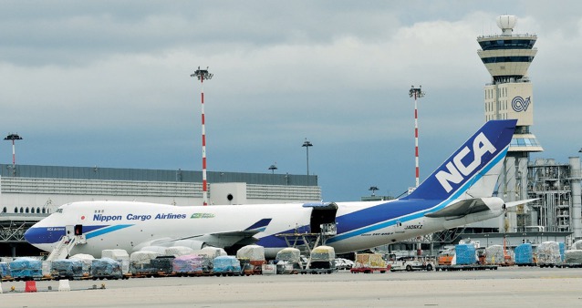 Zboží umístěné na paletách připravené k naložení do letadla Boeing 747-400F  rozměrnými nákladními vraty na boku trupu za pomoci nakládací plošiny