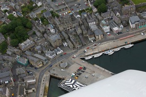 Přístav a střed města Lerwick. Černobílá loď je botel. V současné době je na Shetlandských  ostrovech nedostatek ubytování pro pracovníky na těžebních plošinách v Severním moři a tak   je využíváno a takovéto náhradní řešení.