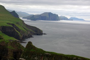 Pohled od západu k východu na jižní pobřeží ostrova Vagar, vzadu ostrůvky Kotlur a  Hestlur