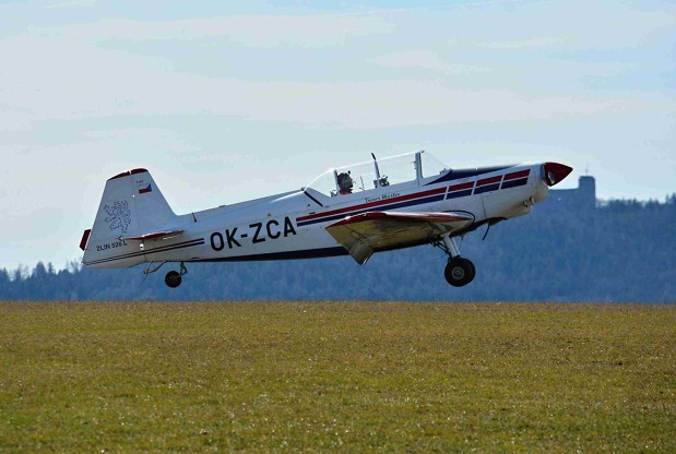 Zlín Z526 z LKPL, s imatrikulací OK-ZCA na finále dráhy 26, v pozadí je dominanta okolí, zřícenina hradu Radyně.